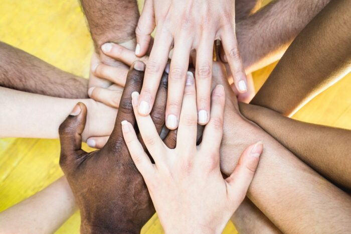 Top view of multiracial stacking hands – International friendship concept with multiethnic people representing peace and unity against racism – Multi racial love and integration between diversity